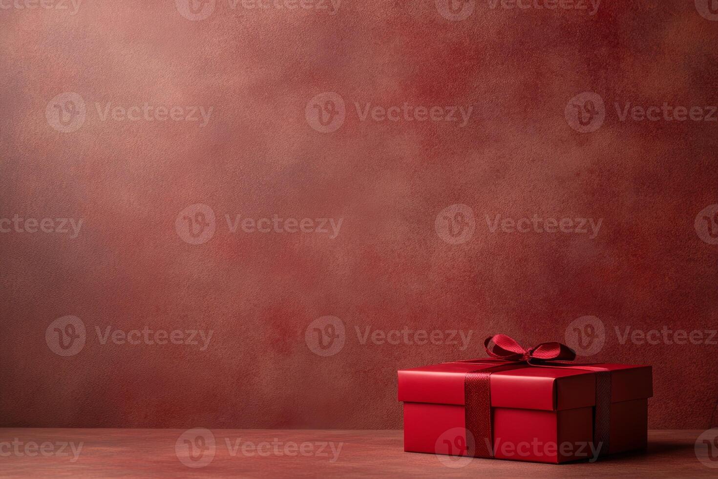 A red gift box with a bow on a textured red background, suggesting celebration or gifting. photo