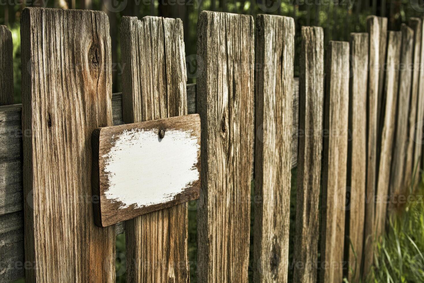 A rustic wooden fence with a blank sign attached, set in a natural environment. photo