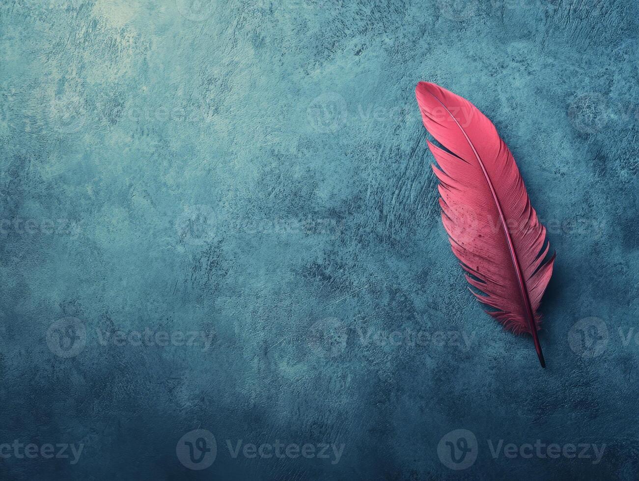 A vibrant pink feather rests on a textured blue background, creating a striking visual contrast. photo