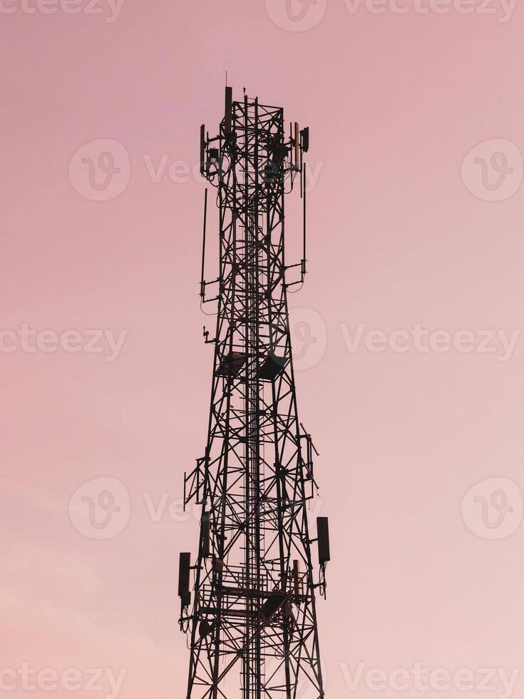 Silhouette of a Communication Tower Against a Vibrant Pink Sunset Sky Capturing Modern Technology and Connectivity in Urban Landscapes photo