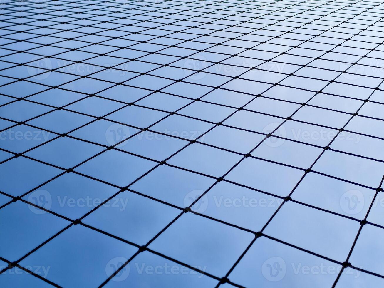 Geometric Pattern of a Wire Fence Against a Clear Blue Sky Capturing Minimalist and Modern Design Elements photo