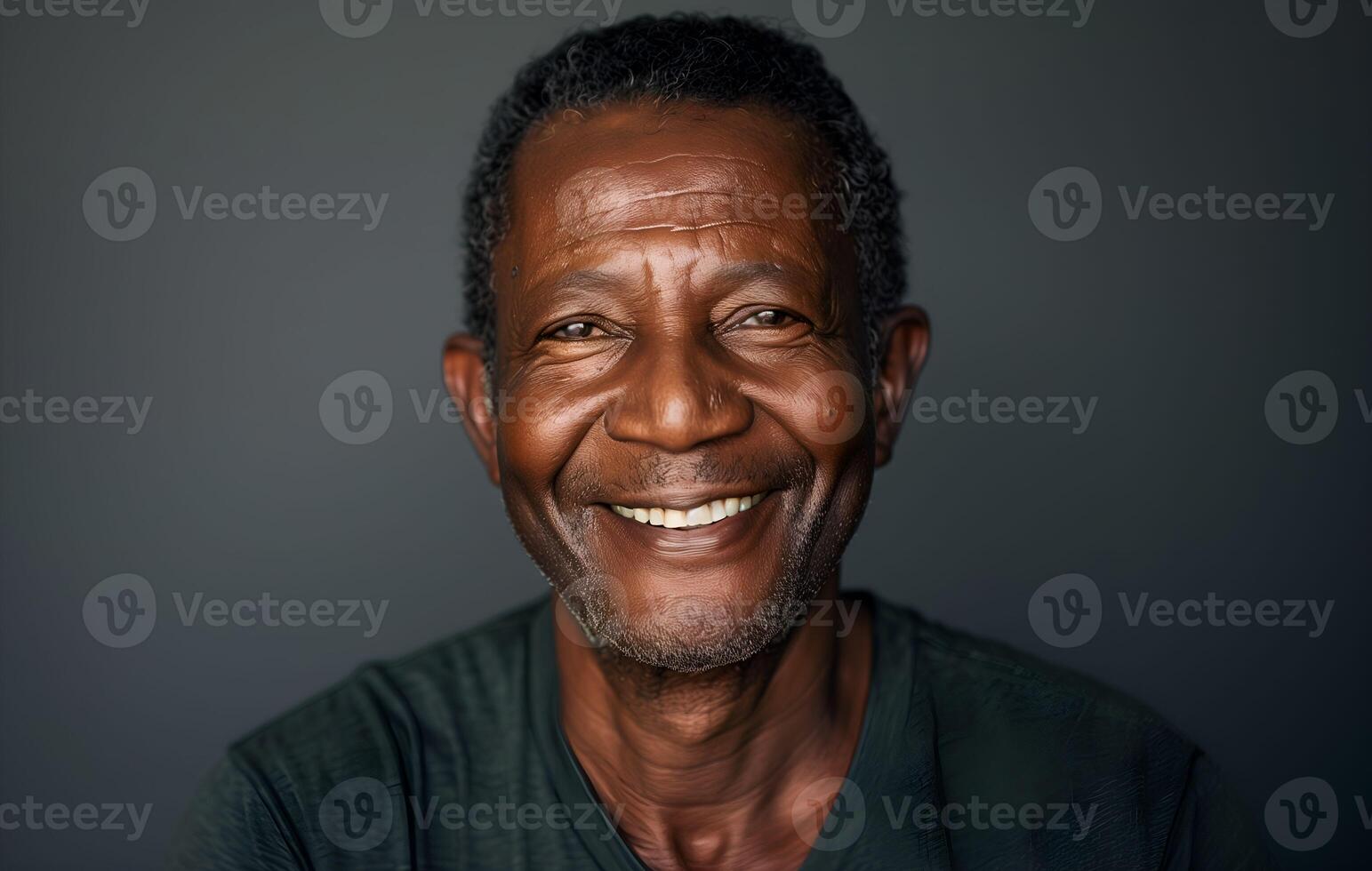 An older black man smiling in front of a gray background photo