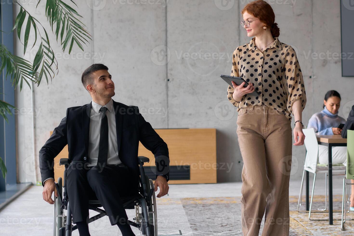 Director in a Wheelchair Engaging in a Business Discussion with a Colleague While Navigating a Modern Office photo
