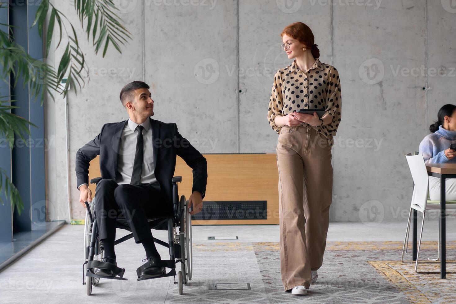 Director in a Wheelchair Engaging in a Business Discussion with a Colleague While Navigating a Modern Office photo