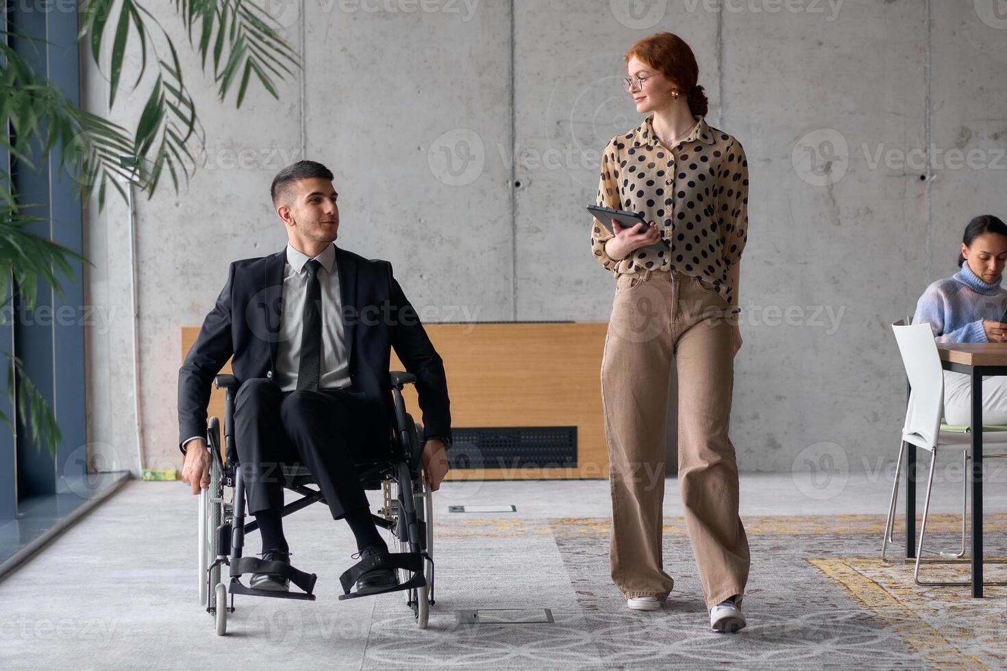 Director in a Wheelchair Engaging in a Business Discussion with a Colleague While Navigating a Modern Office photo