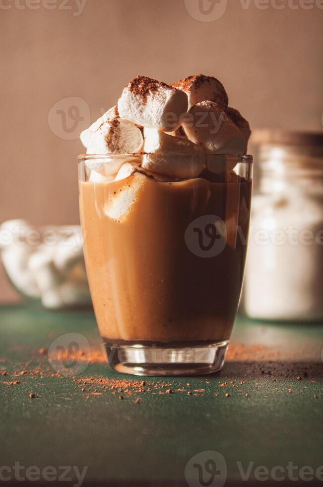 Cozy hot cocoa with marshmallows sprinkled with cinnamon. Christmas beverage concept. Hot cacao, chocolate or coffee in a glass. Vertical photo