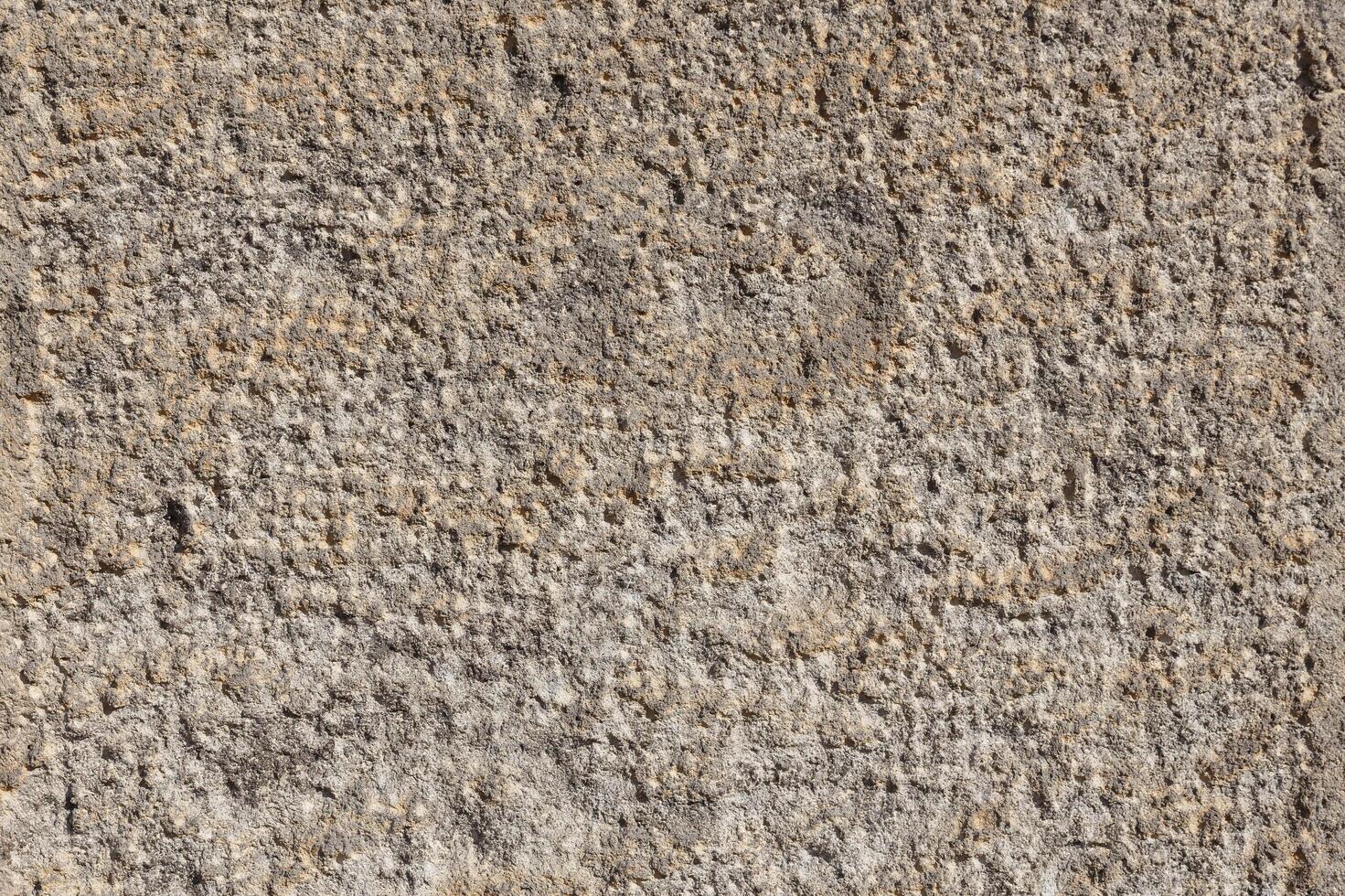 Textured stone wall showcasing ancient carvings under bright sunlight in an archaeological site photo