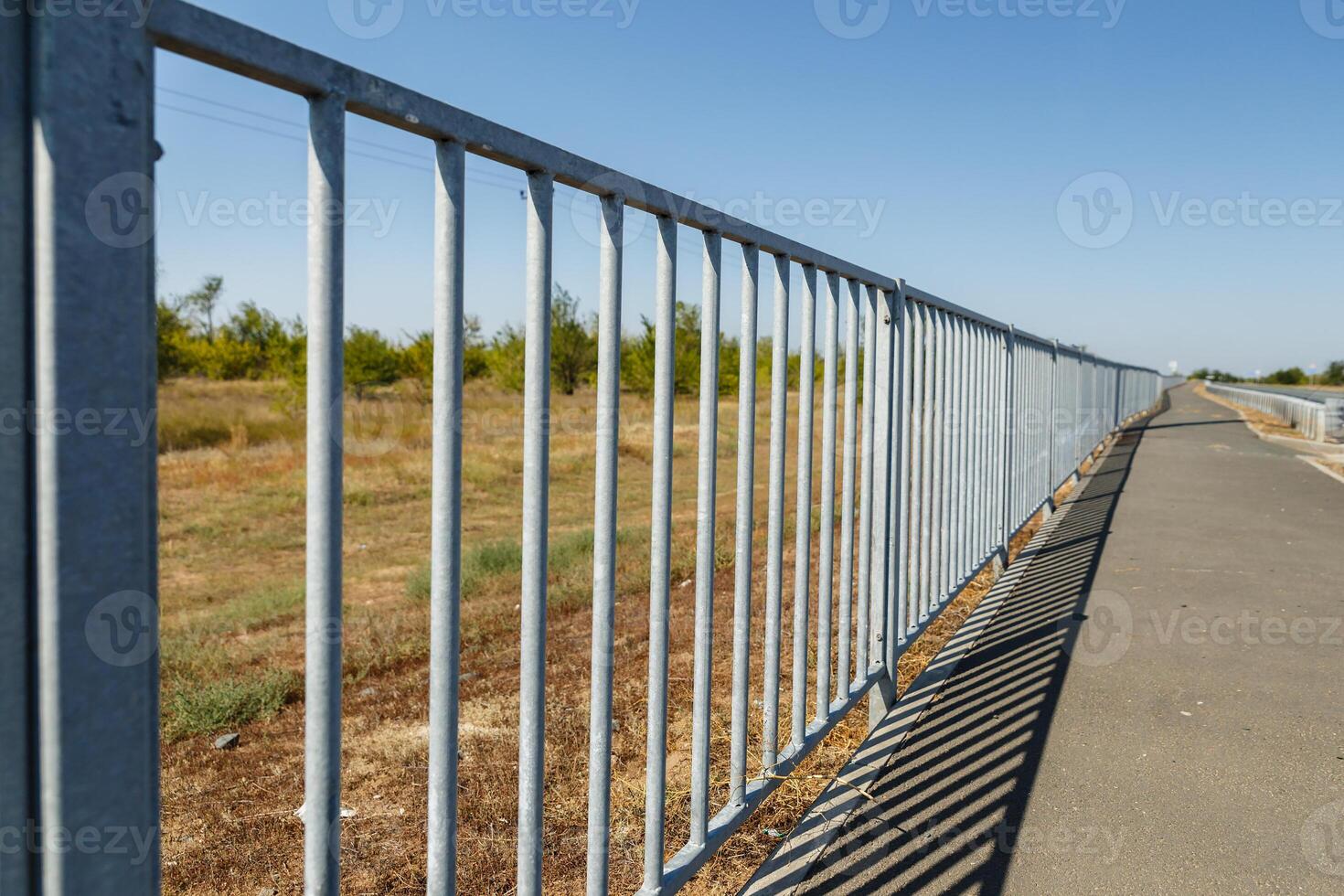 fence between the field and the pedestrian walkway photo