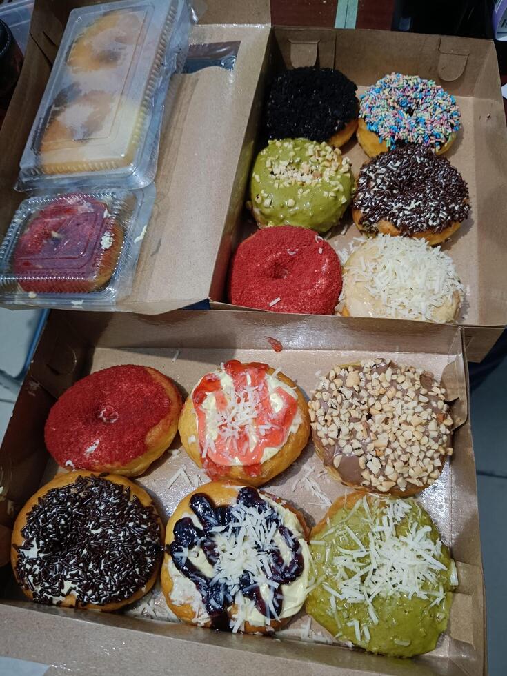 Sweet yellow pumpkin donuts with various topings in paper box ready to eat photo