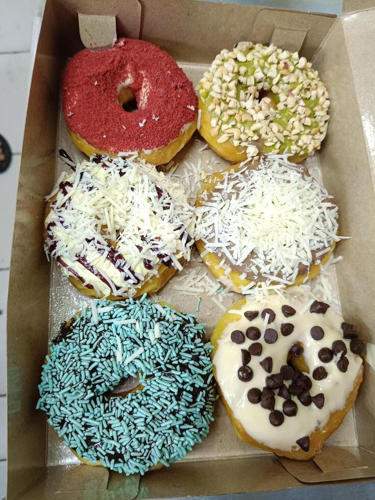 Closeup of sweet donuts with various toppings in paper box photo