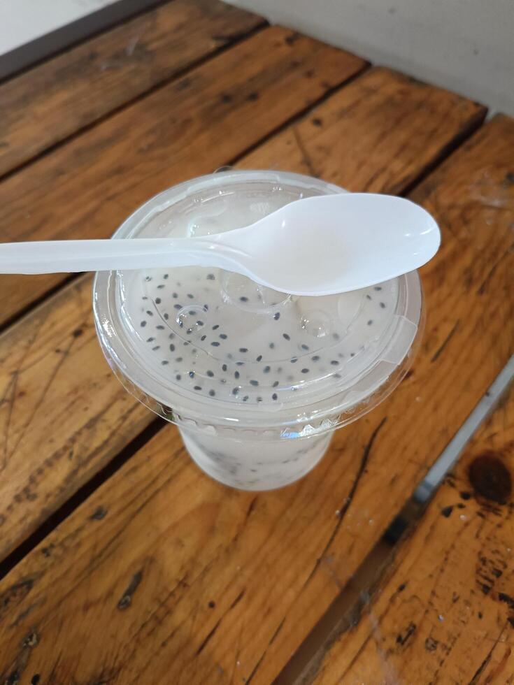 A refreshing plastic glass of soursop flavored drink sprinkled with basil photo