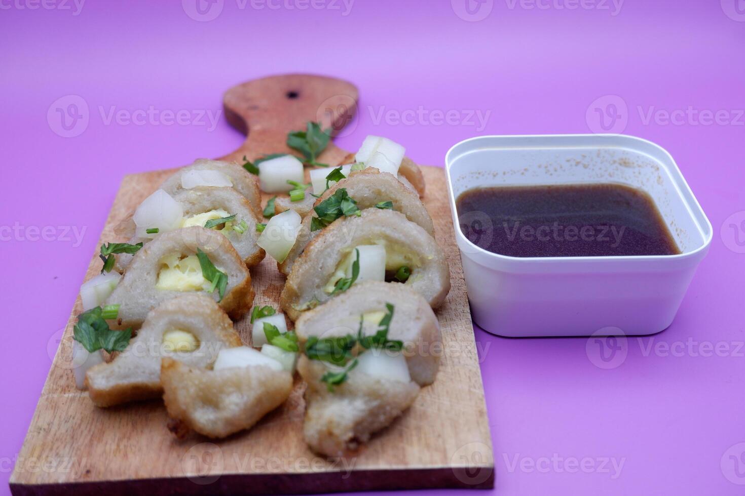 empek-empek on a wooden chopping board isolated on a purple background. typical food from South Sumatra, Indonesia photo