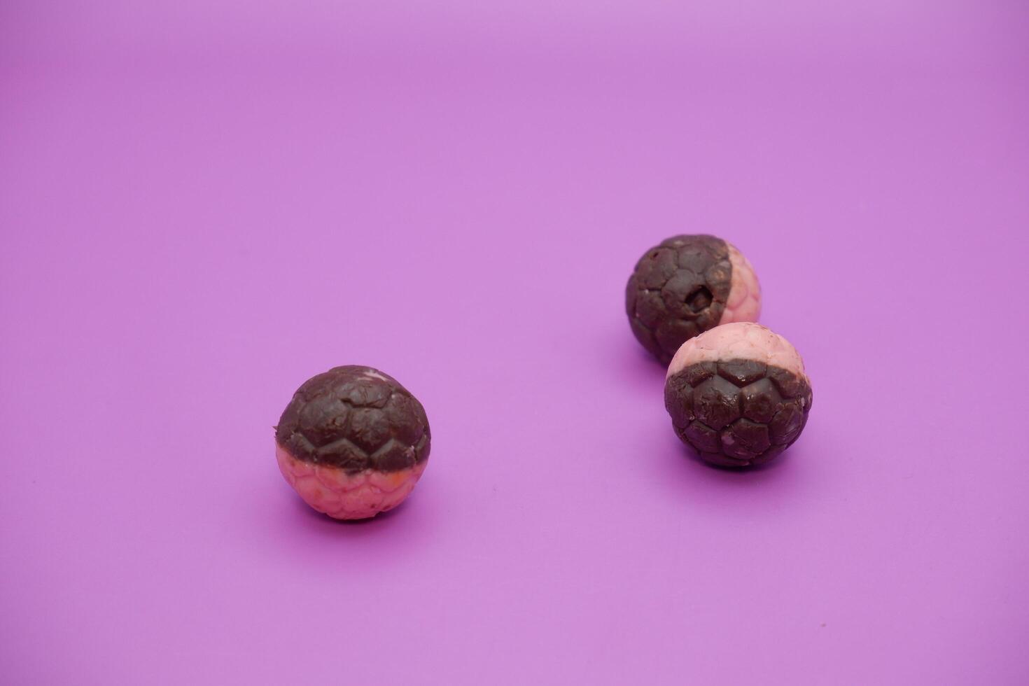Soccer-Themed Chocolate Snack, Half Brown and Pink, Isolated on Purple Backdrop photo