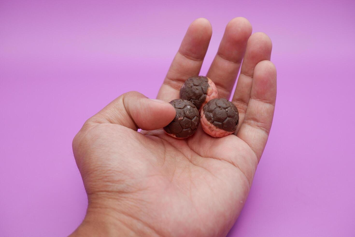 Half pink, half brown chocolate ball snack shaped like a soccer ball held in hand photo
