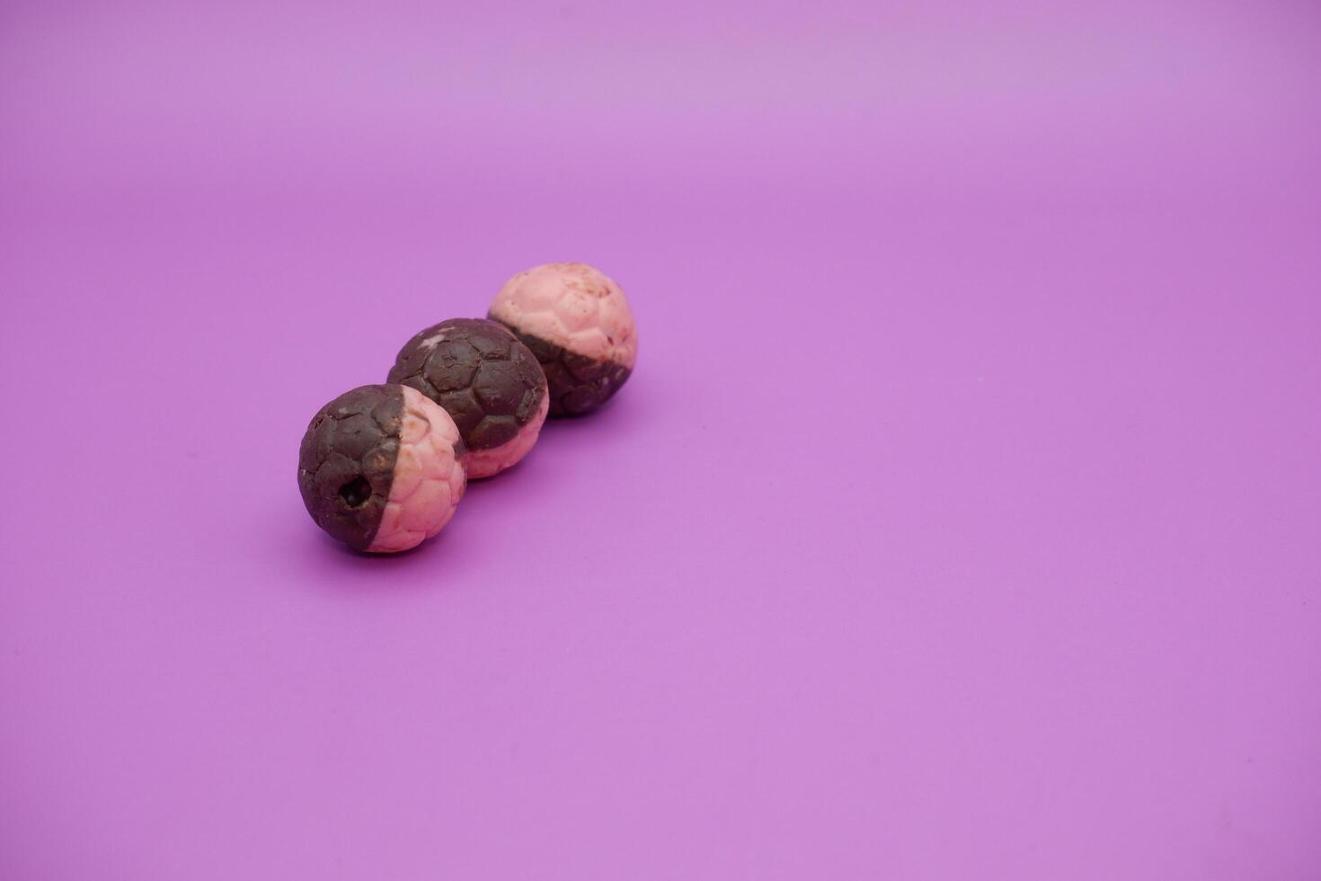 Half Pink, Half Brown Chocolate Ball Snack in Soccer Ball Shape on Purple Background photo