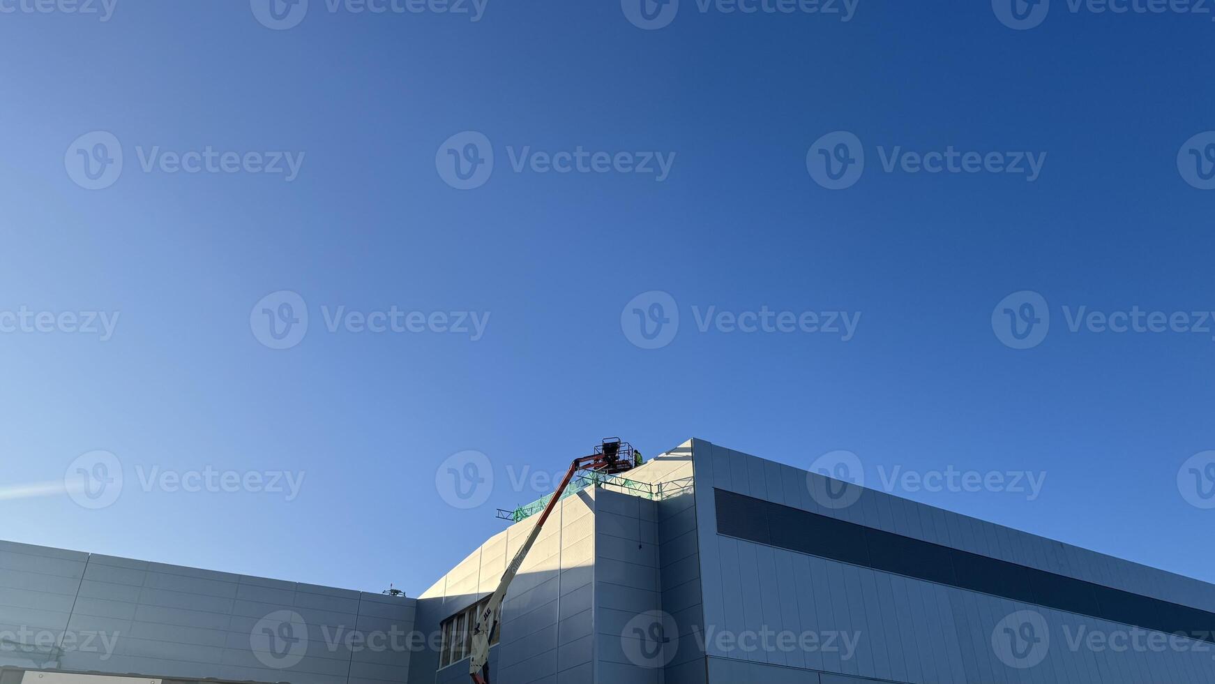 Partial View of Light Gray Building Under Construction with Aerial Lift photo