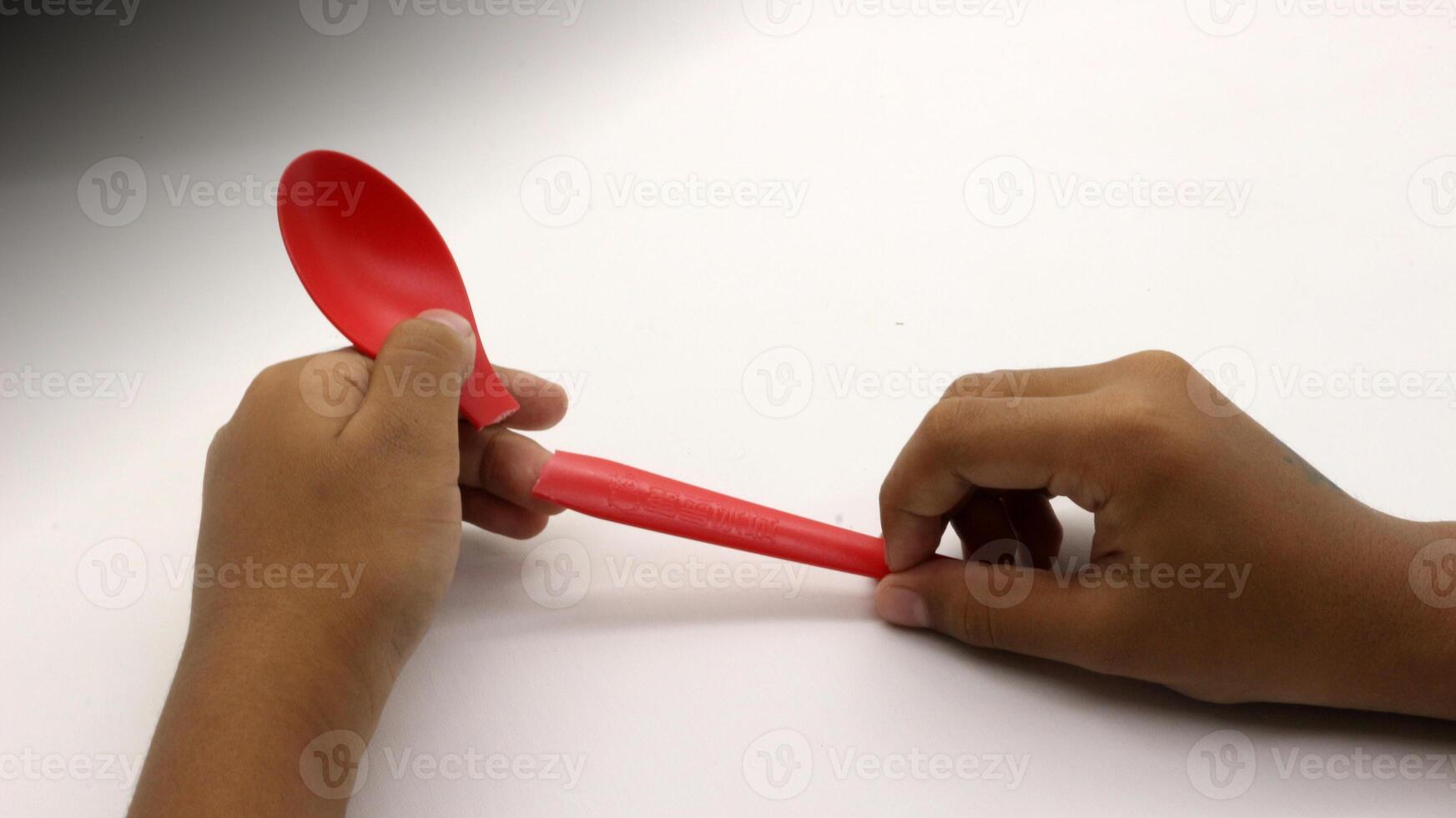 a child's hands are holding two red plastic spoons-3 photo