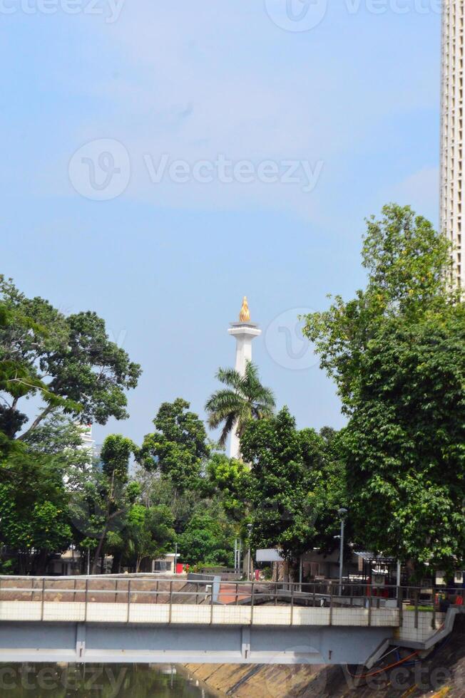 14 April 2024, View of Jakarta National Monument from afar and covered in trees photo