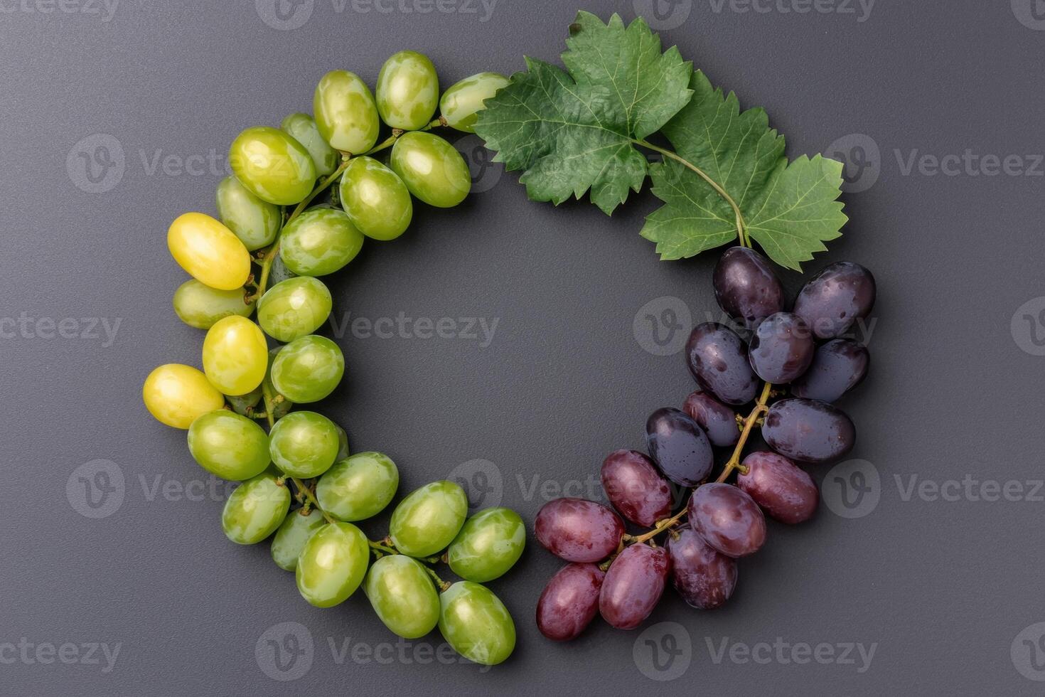 Green, yellow, and red grapes arranged in a circle on a dark background photo