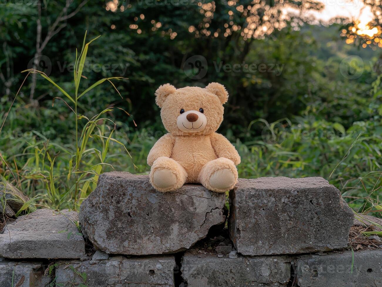 Teddy bear sitting on a stone wall in nature photo