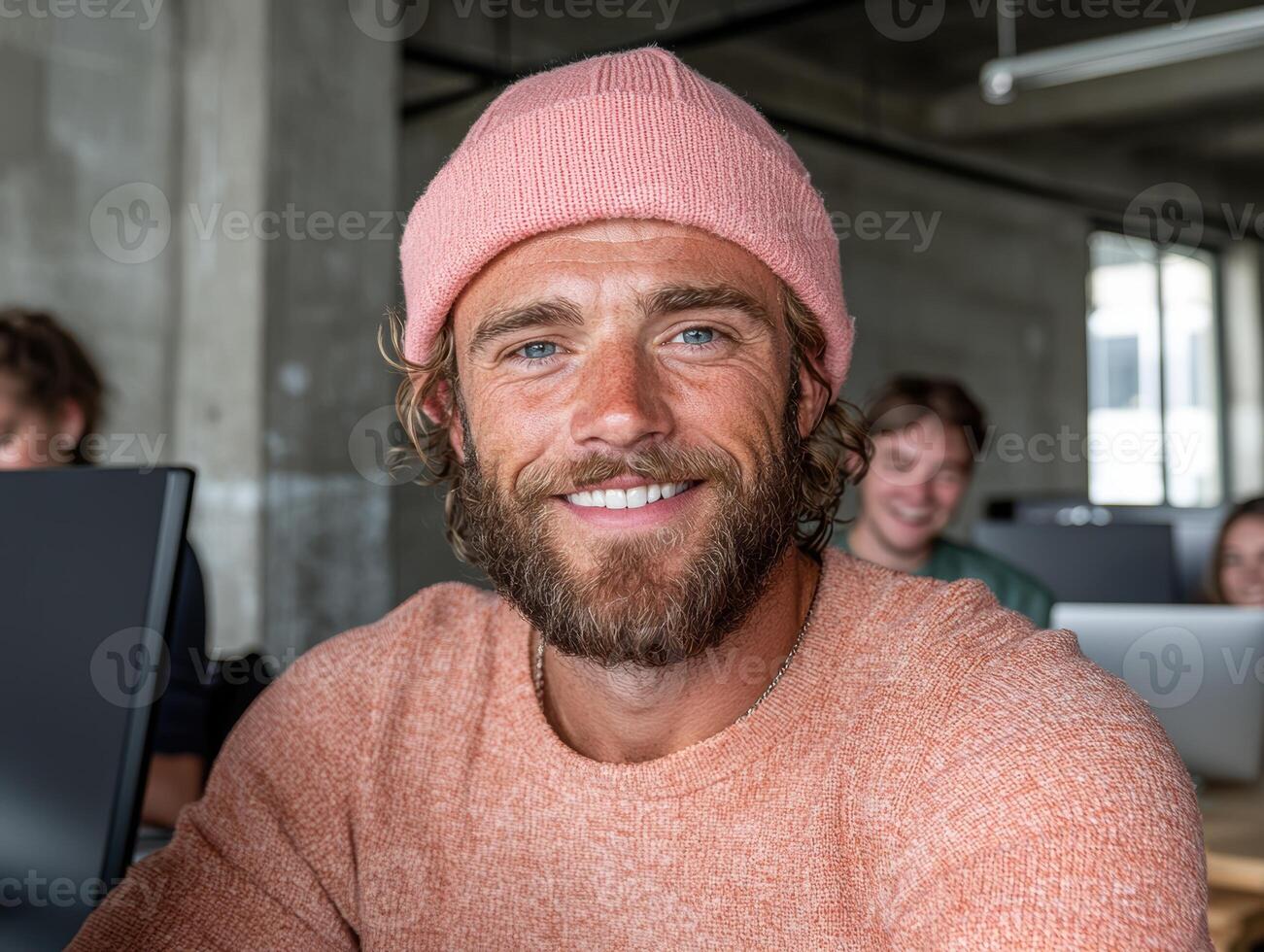 Smiling man in pink beanie working in modern office photo