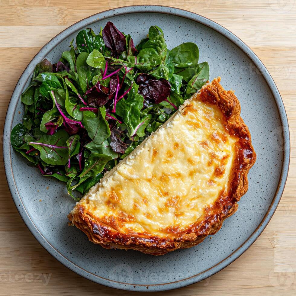 A slice of delicious quiche with a side salad on a gray plate photo