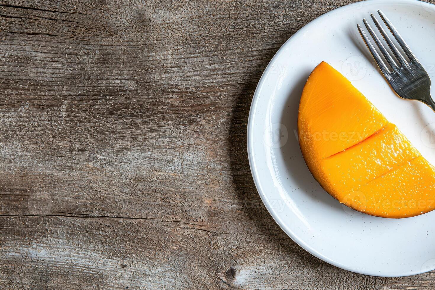 A slice of mango on a white plate with a fork, on a rustic wooden background photo