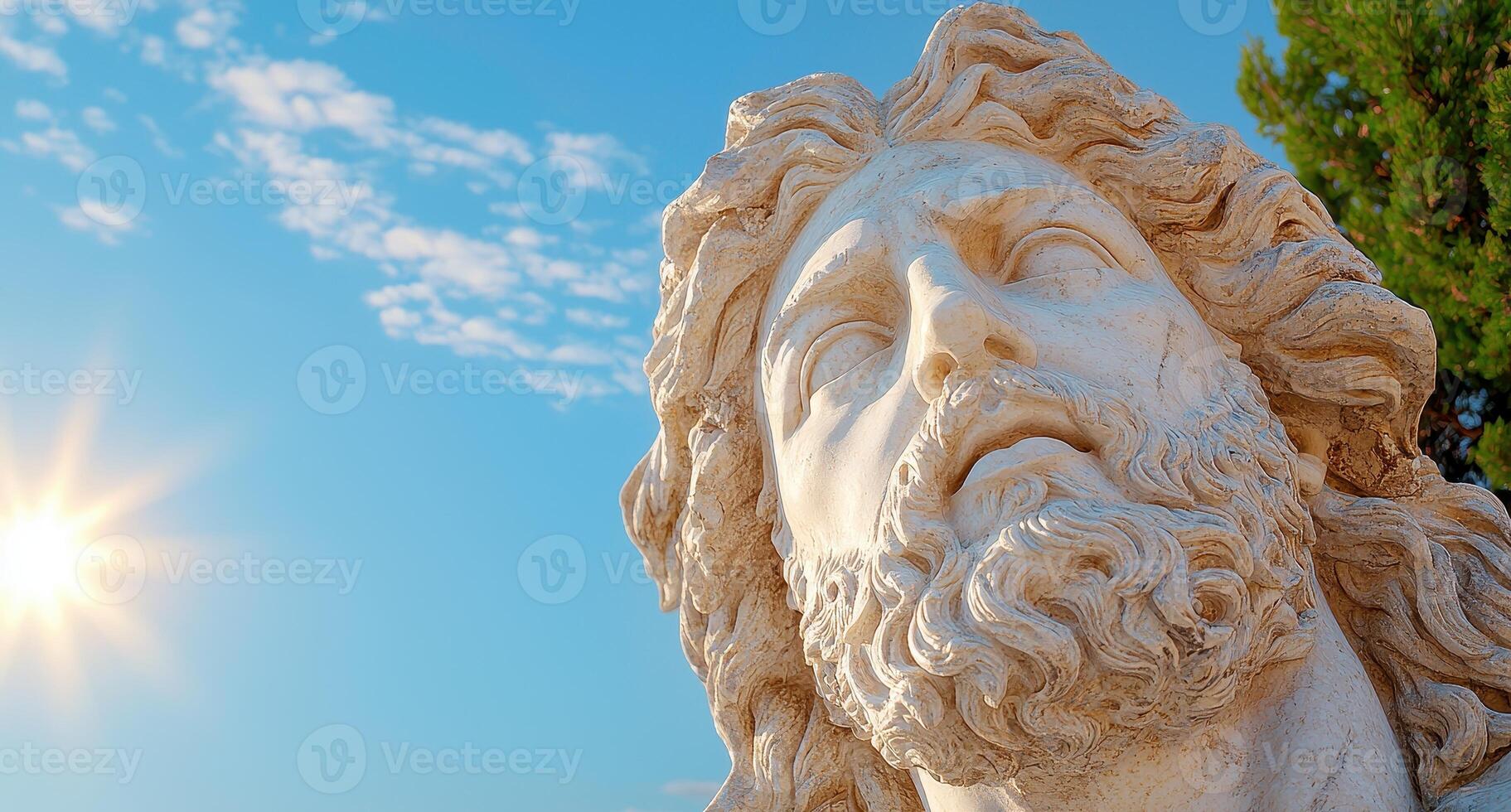 Close up of a serene stone statue face against a bright blue sky photo