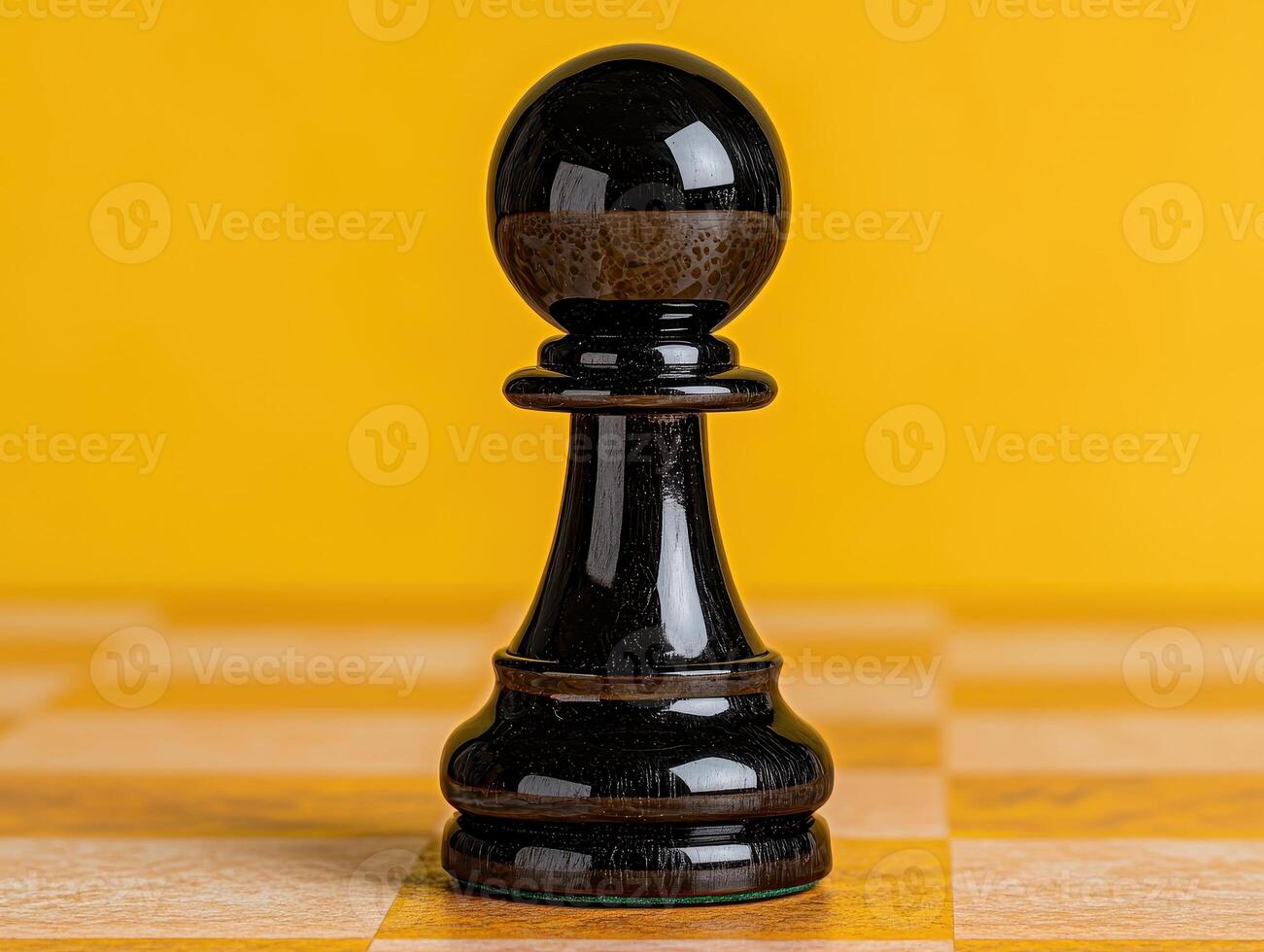 Black chess pawn on a yellow and beige chessboard photo