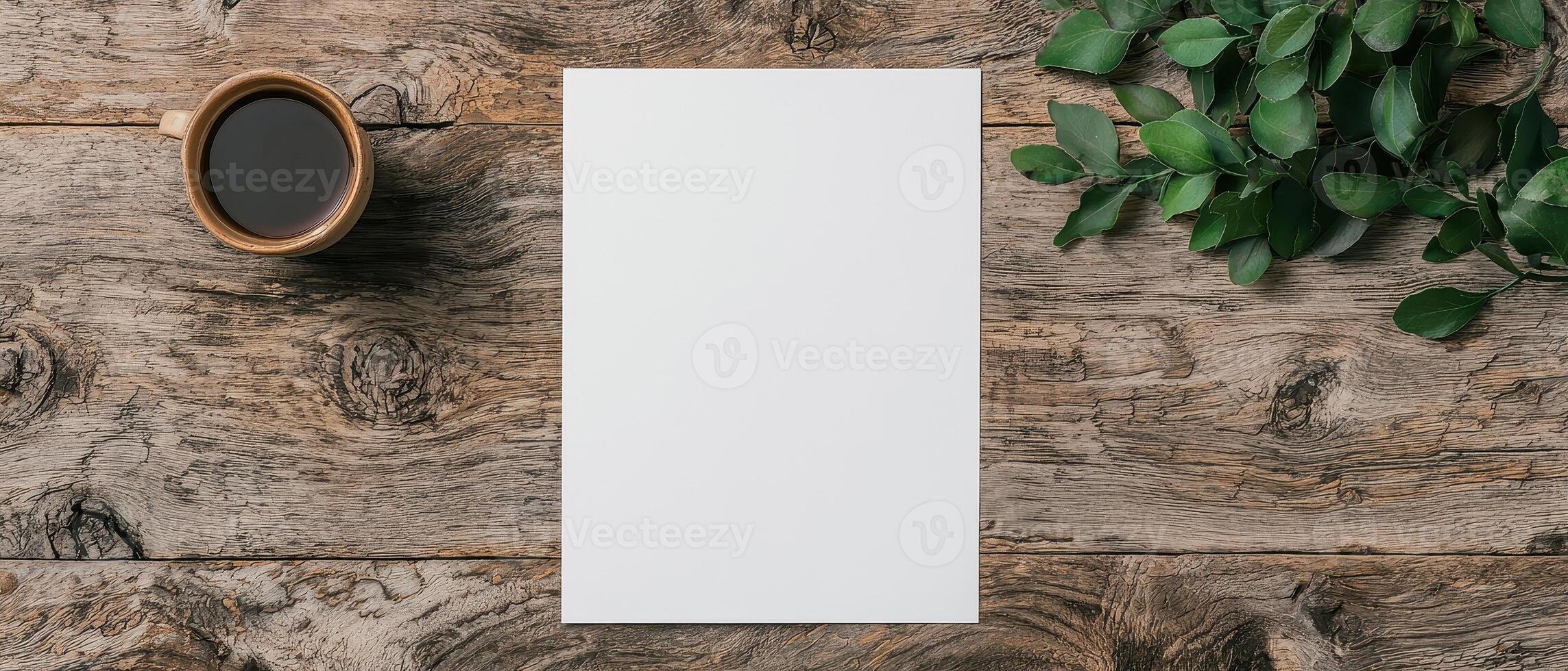 Blank paper mockup on rustic wooden table with coffee and green leaves photo