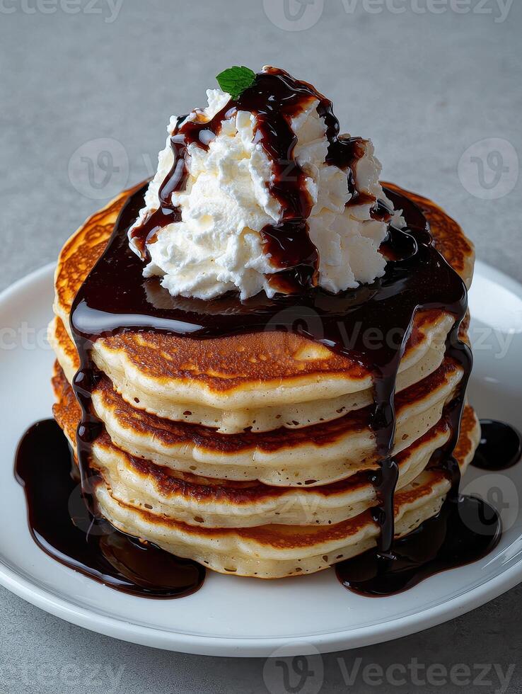 a stack of pancakes with whipped cream and chocolate sauce photo