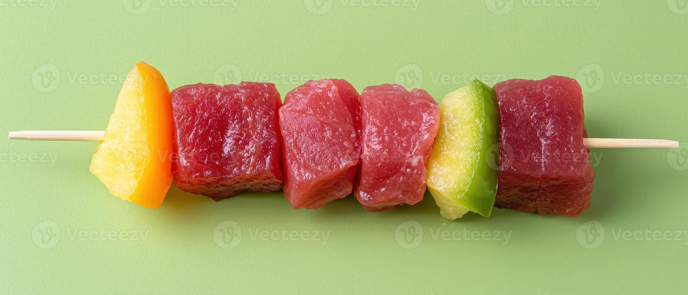 Delicious tuna and fruit skewers on a green background photo