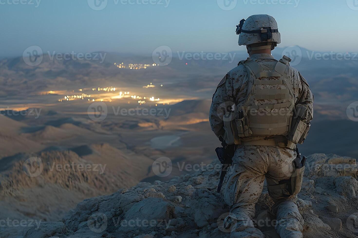 Military Soldier Overlooking Illuminated City at Dusk in Desert Landscape photo