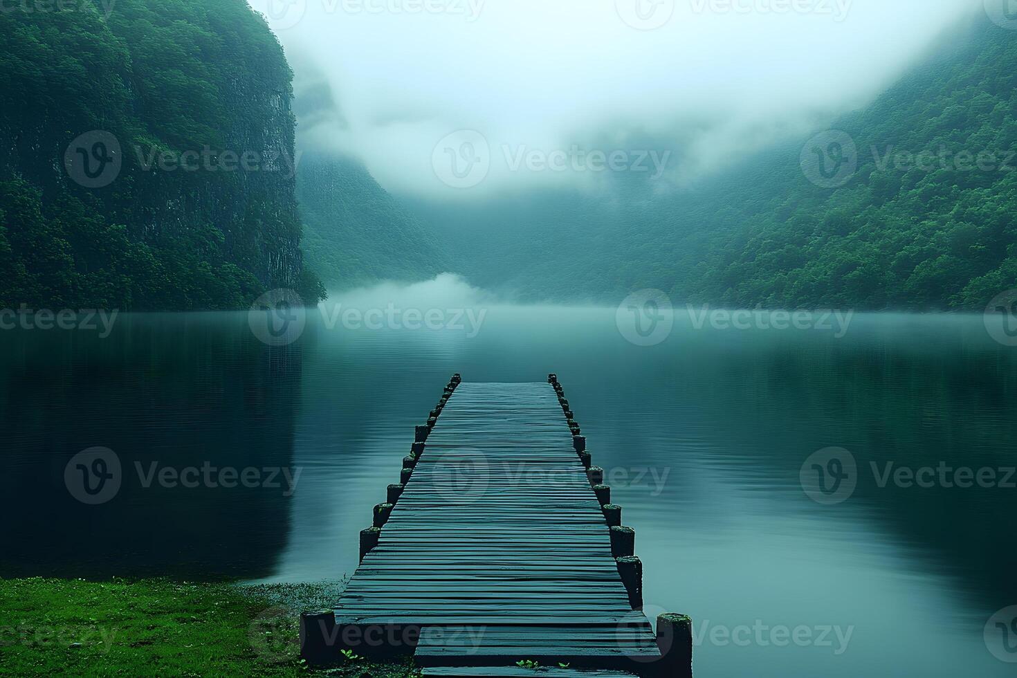 Serene Misty Lake with Wooden Dock and Lush Green Mountains in Fog photo