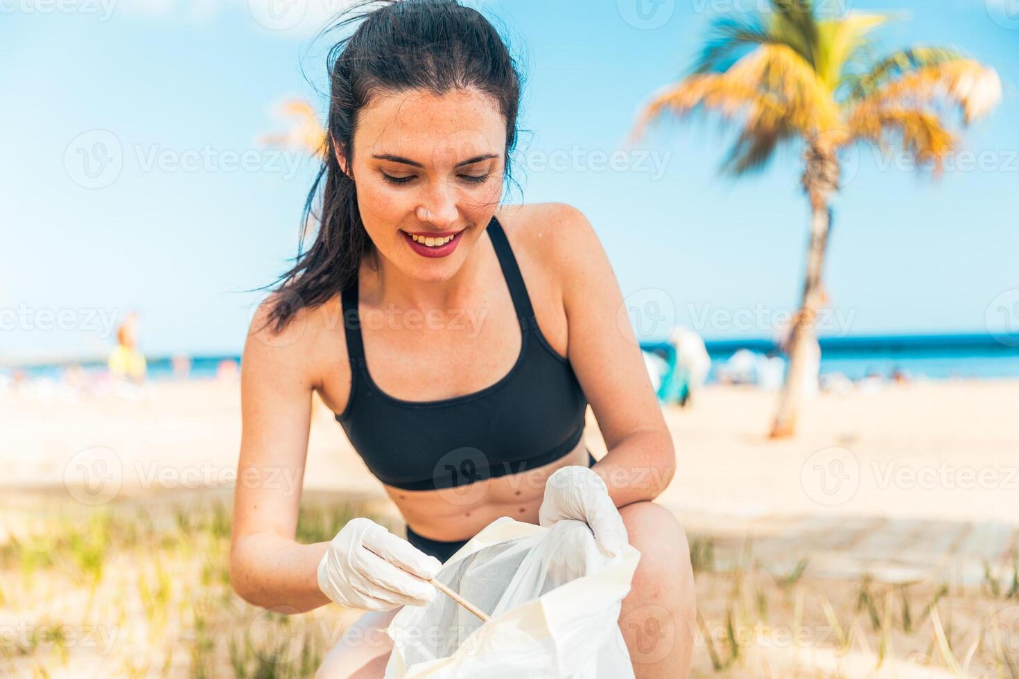 A happy woman is responsibly picking up trash and taking care of the environment photo