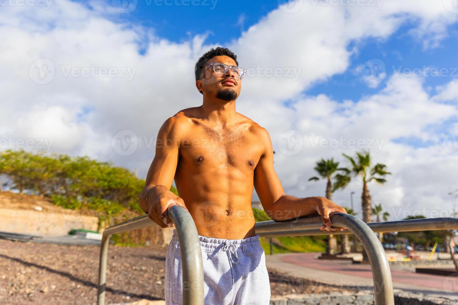 A man with a beard and glasses stands between bars during a workout photo