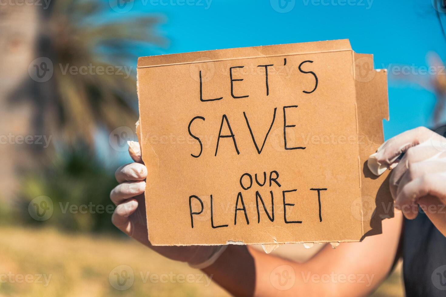 A person holding a sign that says Let's save our planet photo