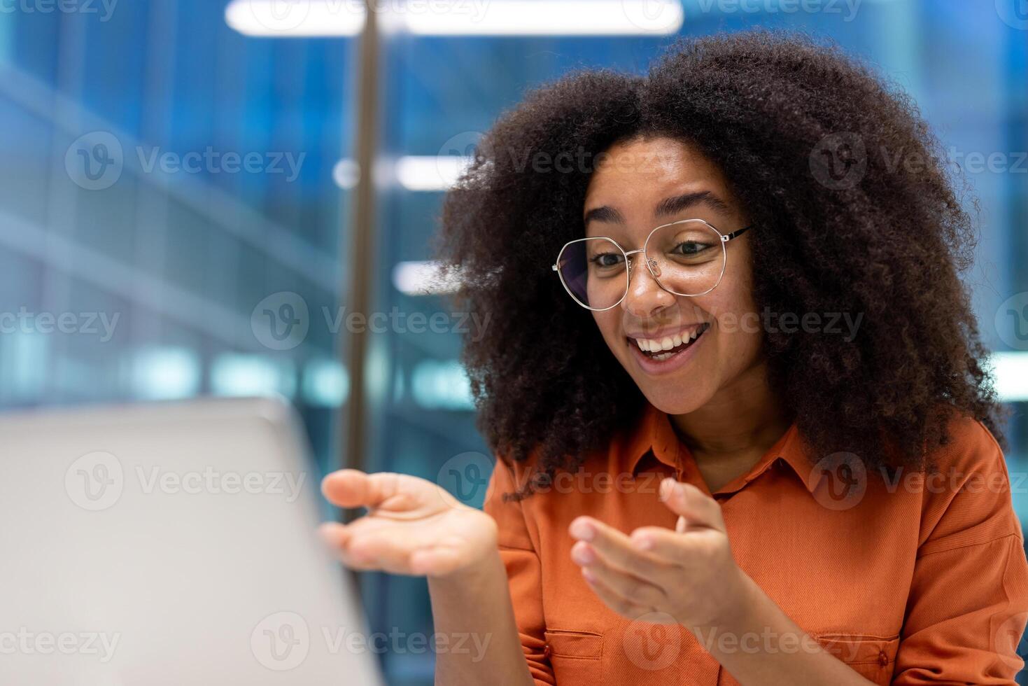 Happy woman in glasses interacting during online meeting on laptop, showing confident and positive attitude. Expressive body language reflects engagement and enthusiasm. photo