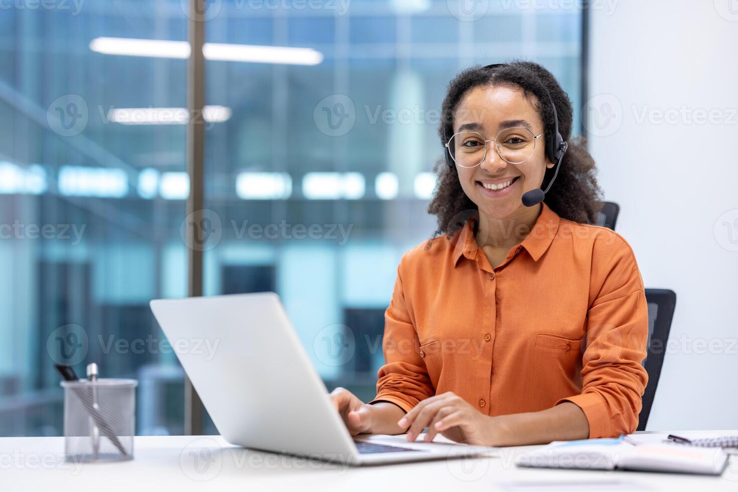 Happy customer service professional wearing headset, working at office desk with laptop, embodying friendly business communication, technology, and support. photo