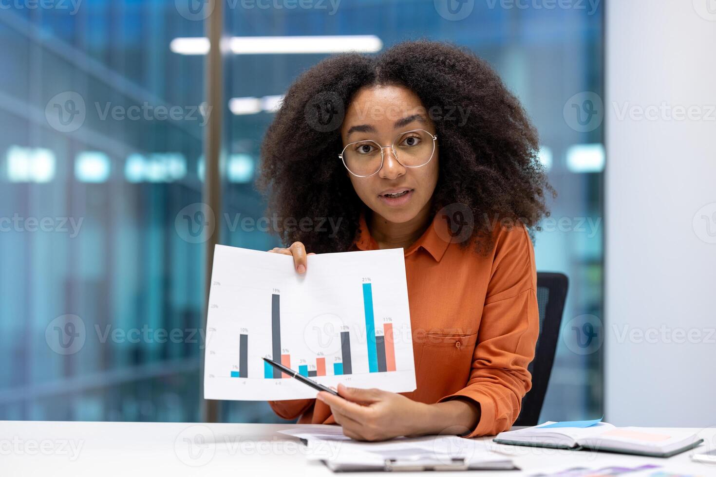 A professional woman explains data trends using graphs during a business meeting in a modern office. Her presentation focuses on statistical analysis while fostering teamwork and professional growth photo