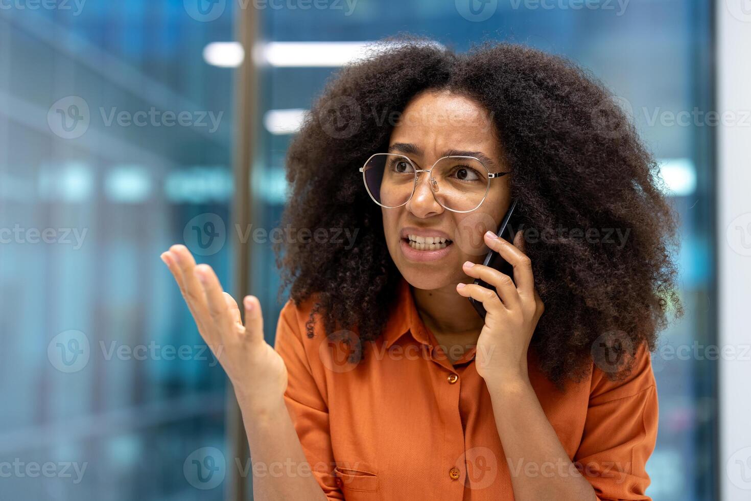 Frustrated businesswoman talking on phone, expressing anger with hand gestures. Captures emotion and stress in workplace communication, typical of busy office environments. photo