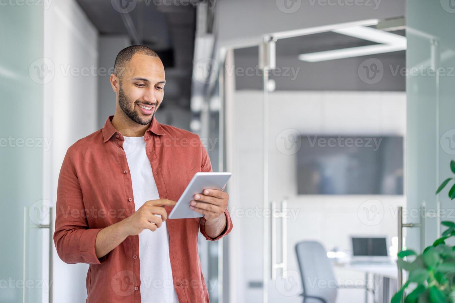 Successful satisfied businessman using tablet computer inside office at workplace, man in casual shirt reading online report, programmer developer testing new software. photo