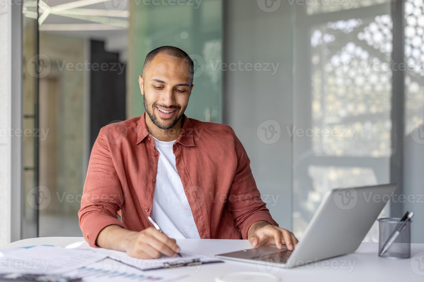 Portrait of a young successful financier, a man behind paperwork, filling out tax forms, and investment reports. Businessman at workplace with documents and laptop. photo