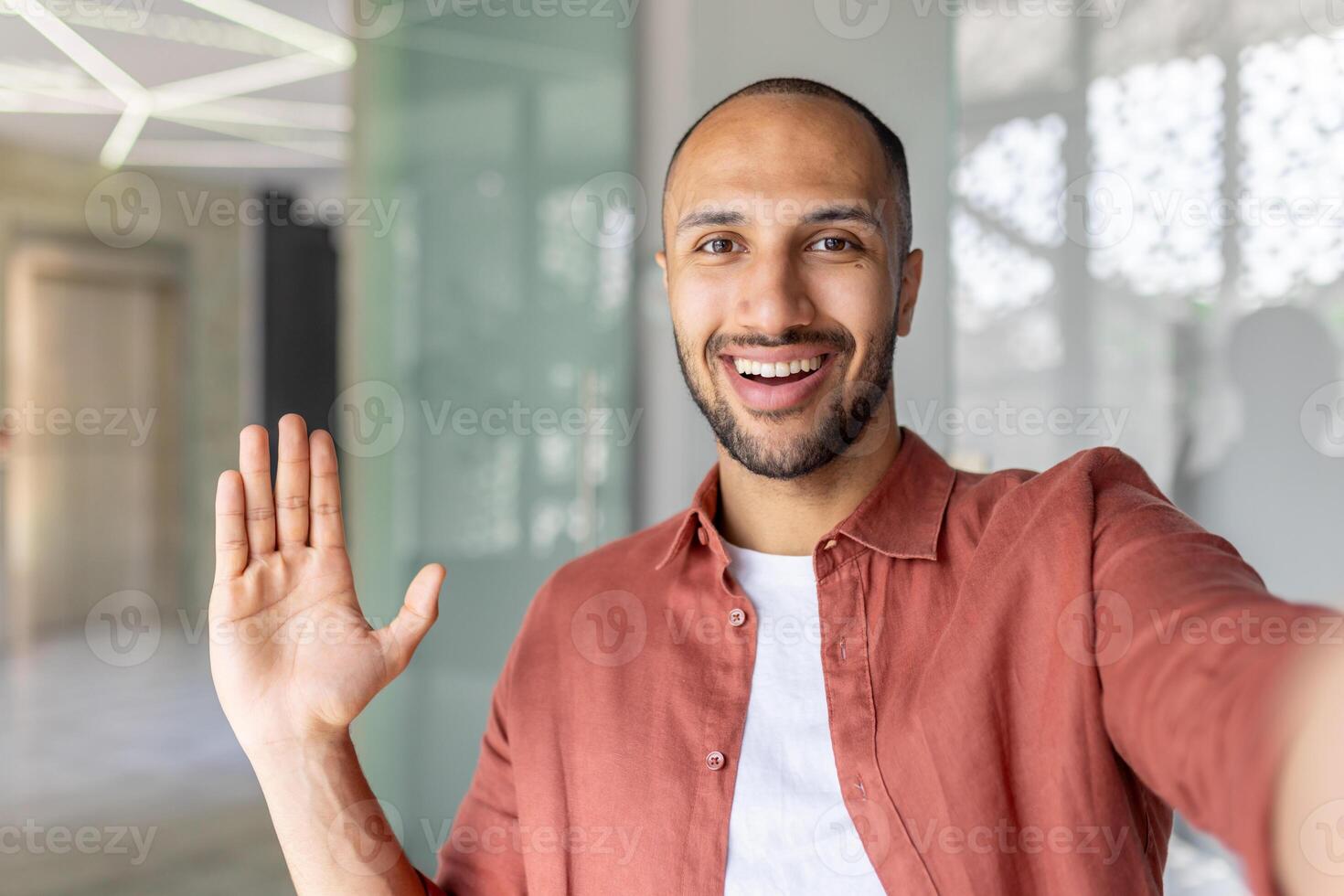 Joyful man looking into phone camera, talking to colleagues and partners remotely using call, office worker at workplace inside office. photo