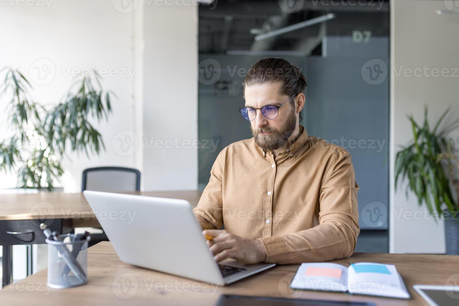 Focused professional using a laptop at a desk in modern office. Concept of productivity, business, and technology usage in a professional workspace. photo