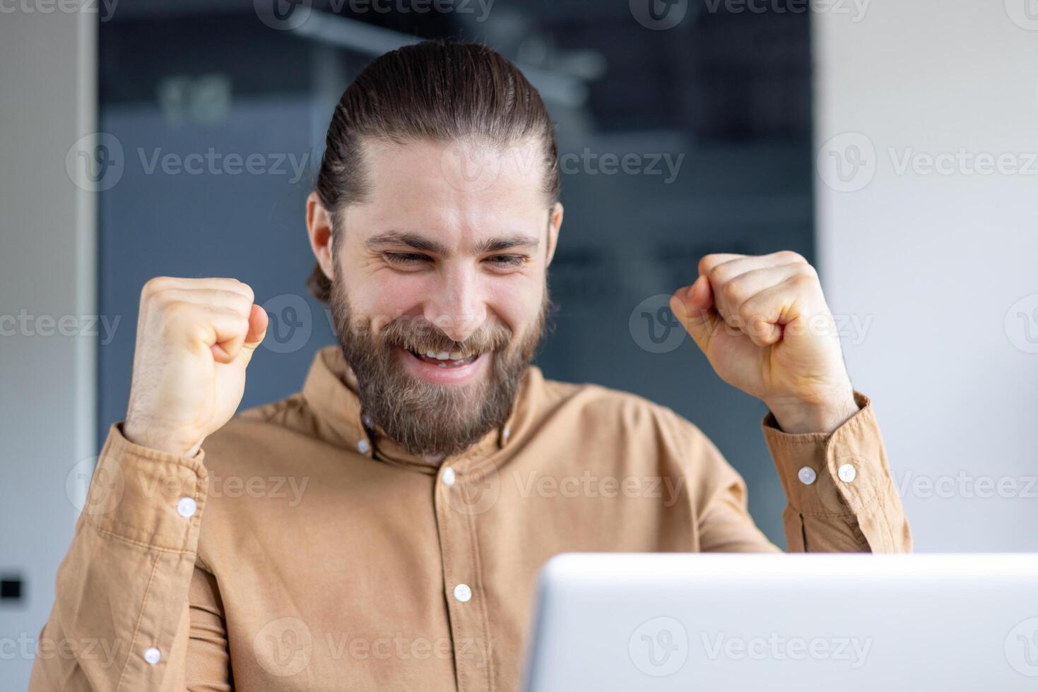 A man in a professional setting is enthusiastically celebrating a personal or professional success. He is expressing joy and victory through his emotions and body language. photo