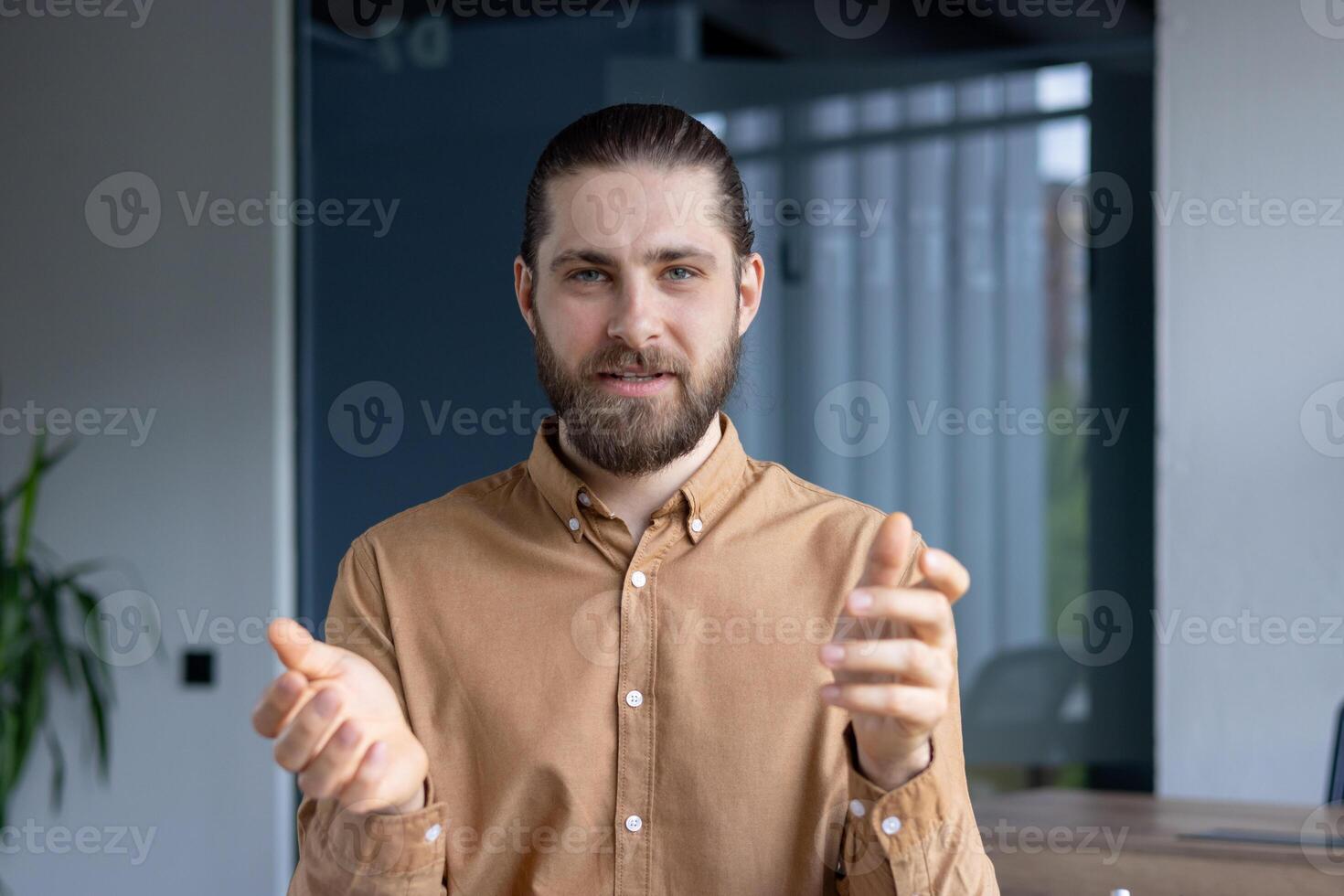 A professional-looking man gestures expressively during a presentation or collaborative meeting in a modern office setting. photo