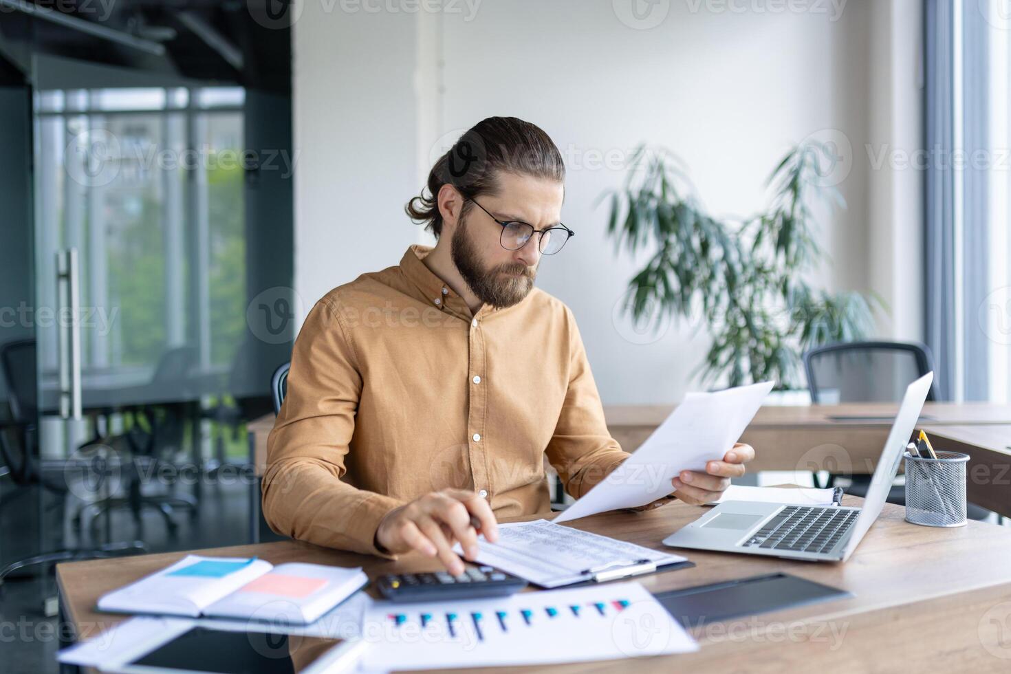 A focused business professional working at their desk, analyzing documents and data with precision in a modern office environment. photo