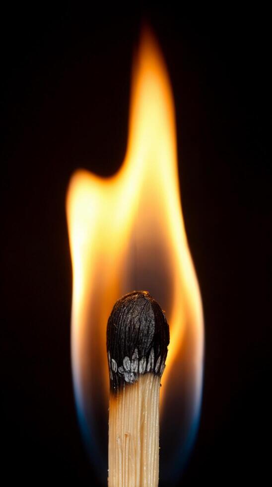 A fully lit matchstick with a bright flame burning in the dark photo