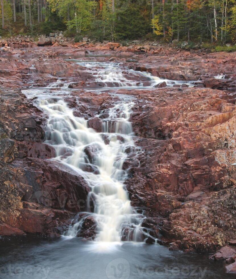 Long exposure of a waterfall Brattfallet on red rocks, in Varmland, Sweden. photo